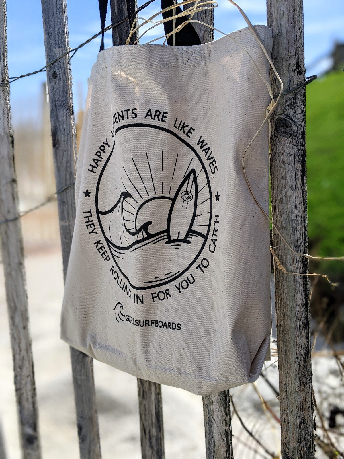 happy moments tote bag hanging on fence